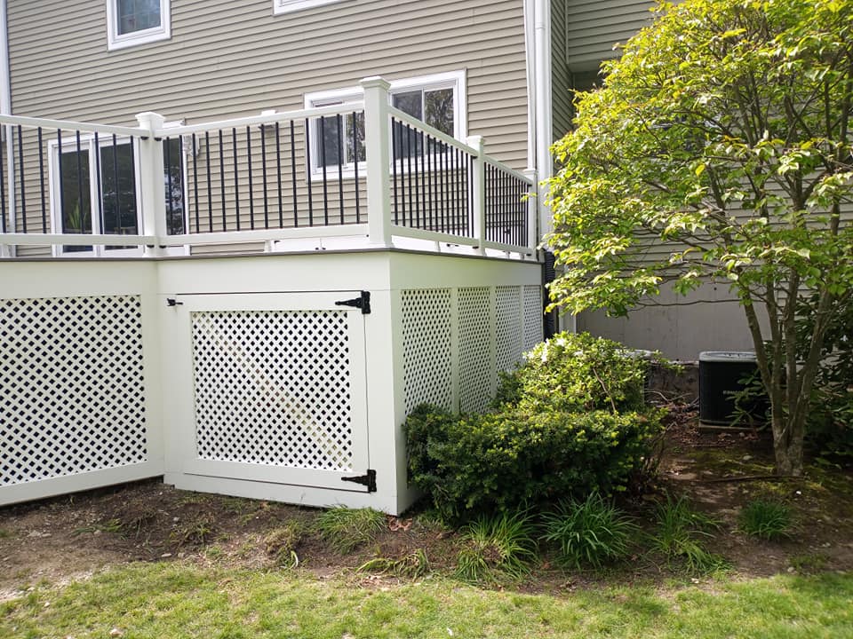 A white deck with a black railing and a fence in front of a house.