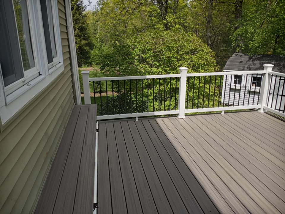 A wooden deck with a white railing and trees in the background