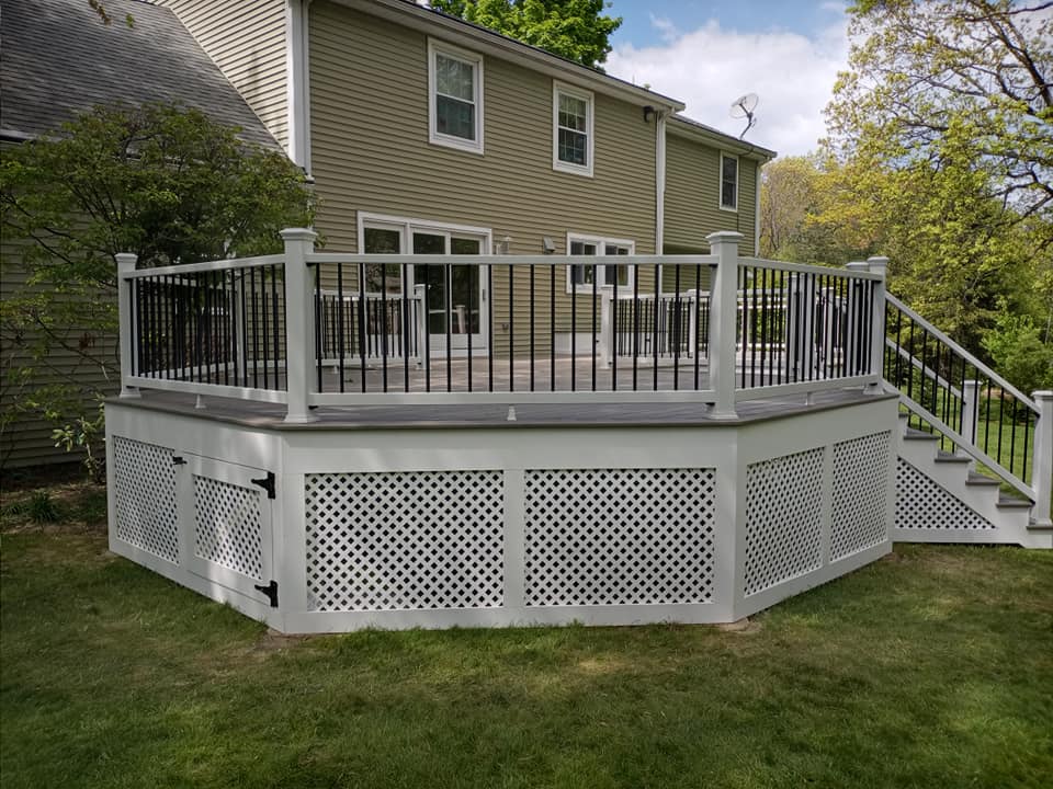 A large deck with stairs and a fence in front of a house.