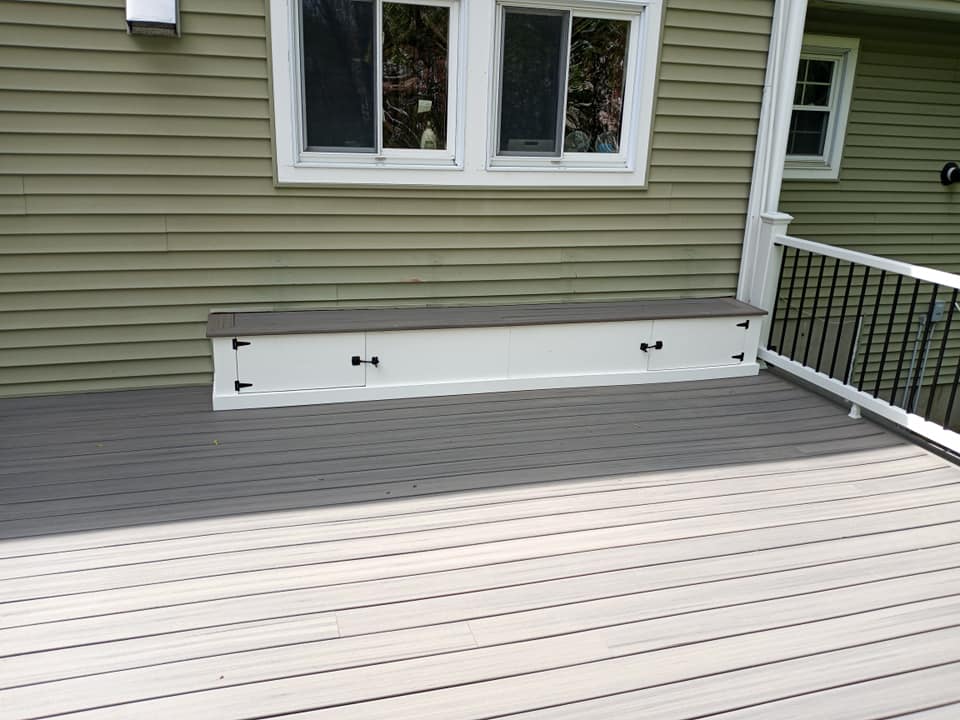 A deck with a bench under a window next to a house