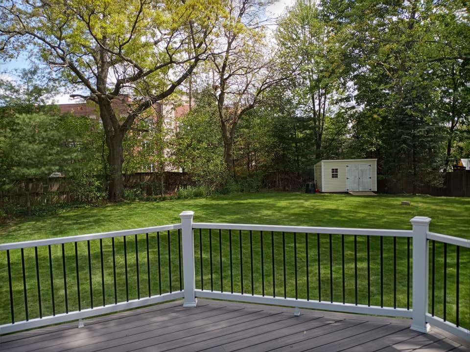A deck with a white railing and a shed in the backyard.