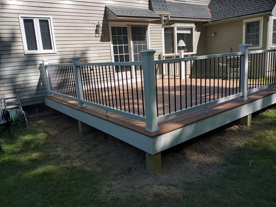 A white deck with a black railing is in front of a house.