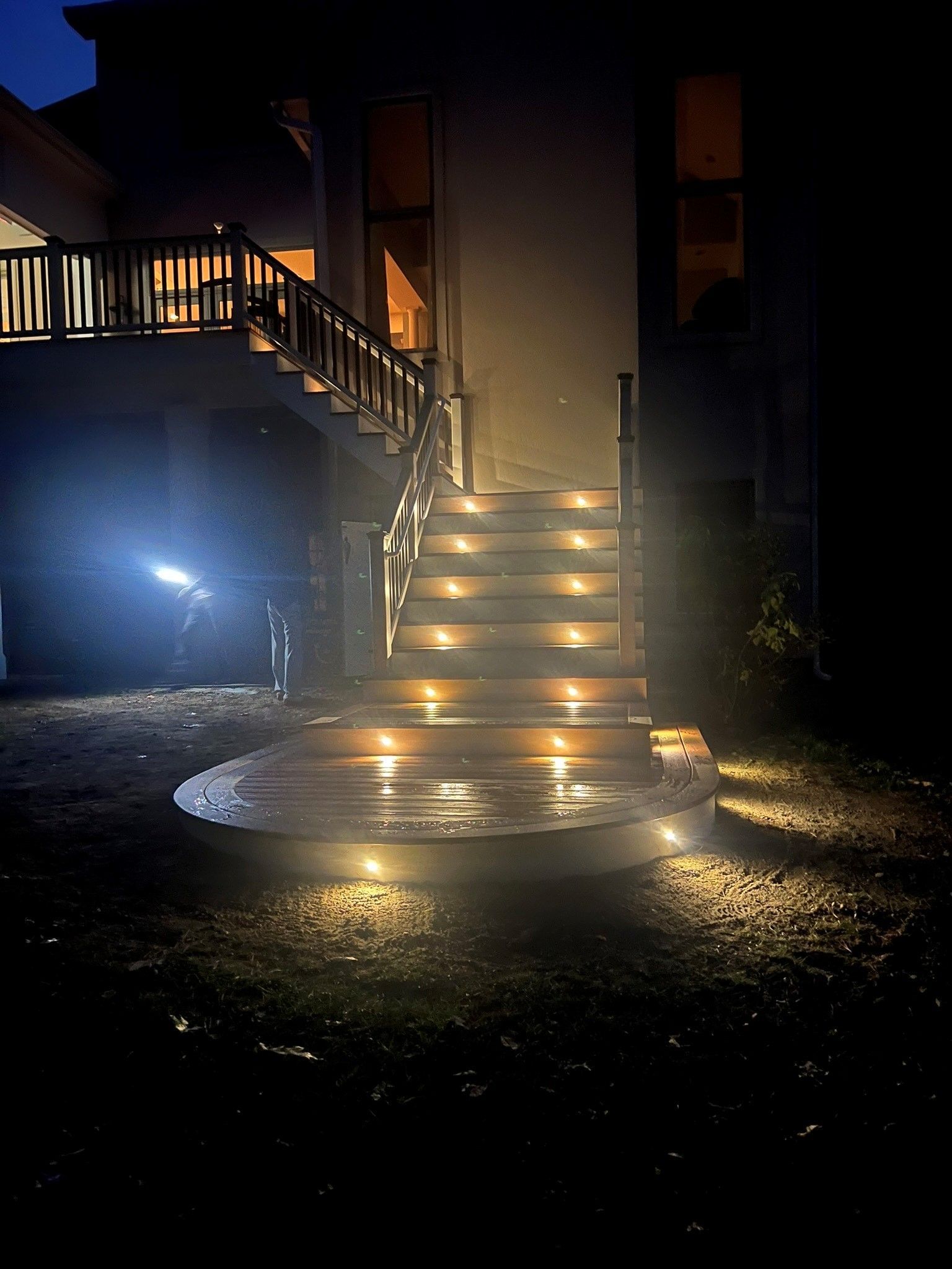 A set of stairs with lights on them in front of a house at night.