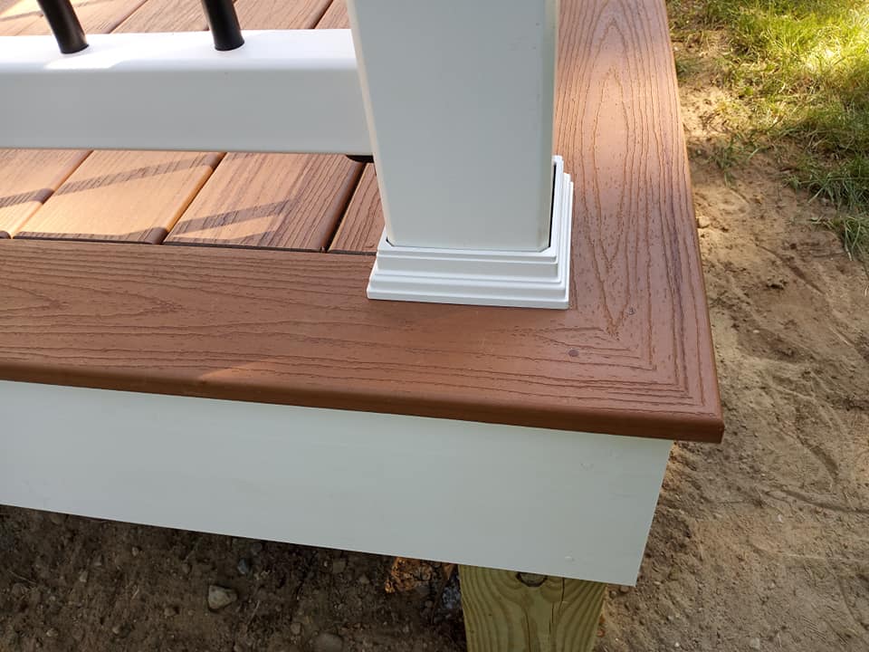 A wooden deck with a white railing and a white post.