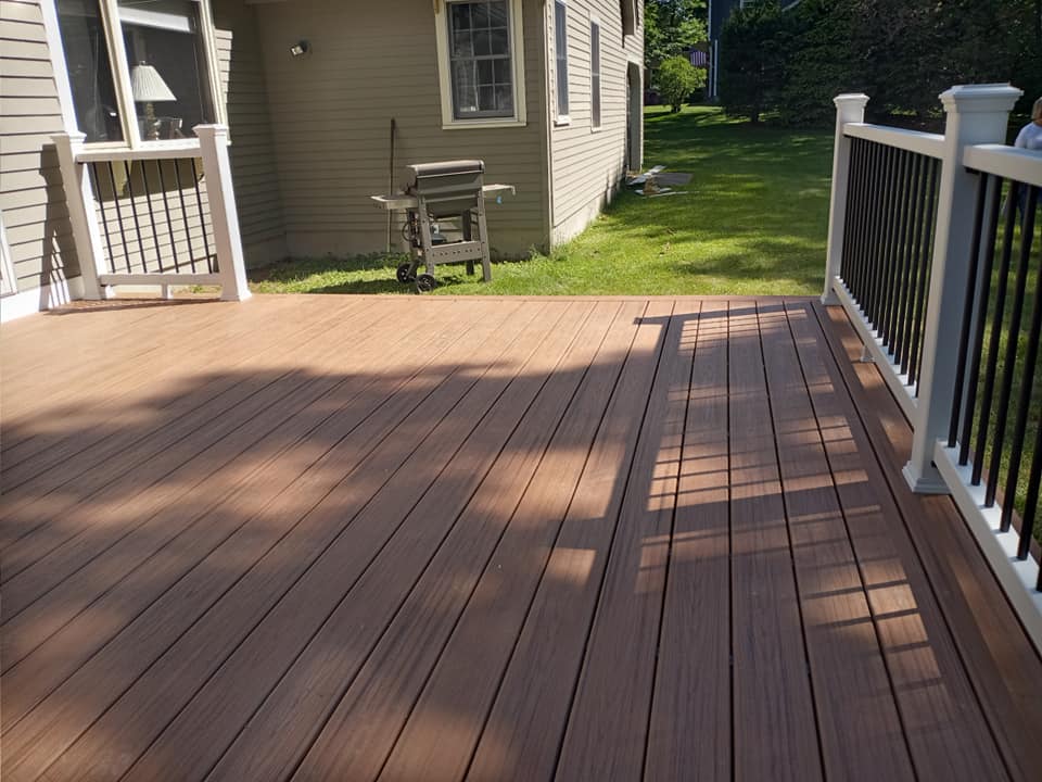 A wooden deck with a white railing in front of a house
