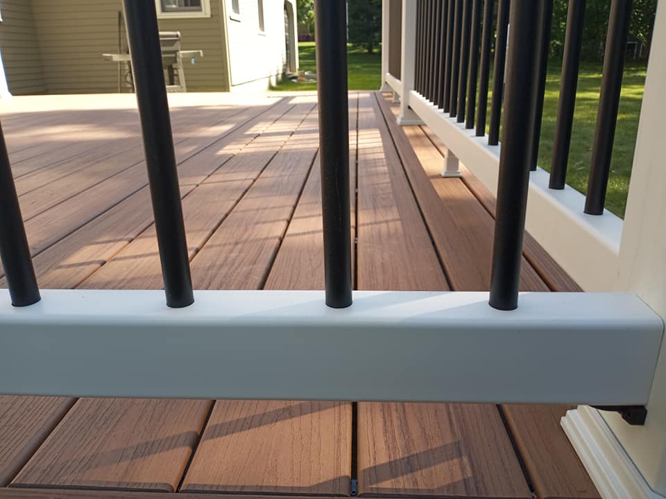 A deck with a white railing and black poles