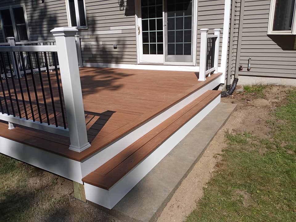 A wooden deck with a white railing is in front of a house