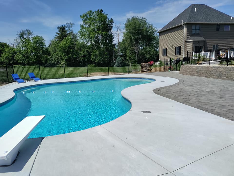 A large swimming pool with a diving board in front of a house