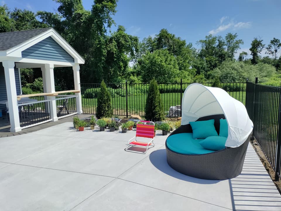 A patio with a couch and chairs and a gazebo in the background