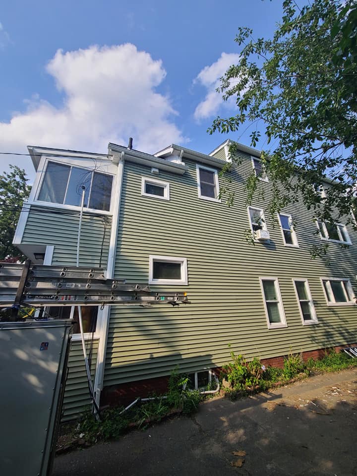 A green house with a lot of windows and a blue sky in the background.