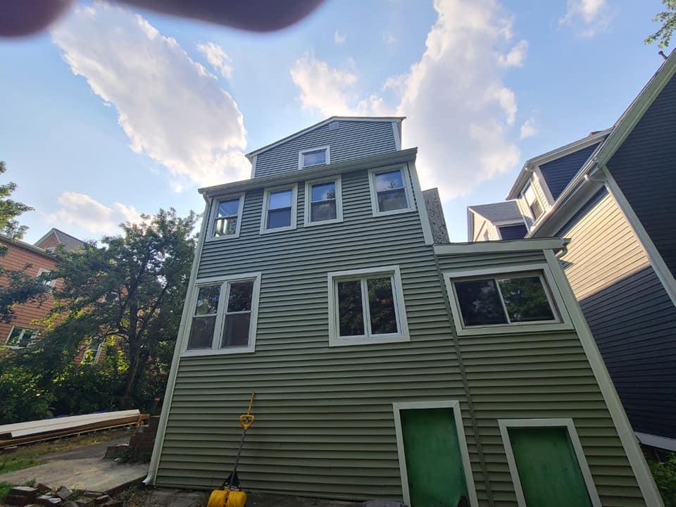 A green house with a lot of windows and a blue sky in the background.