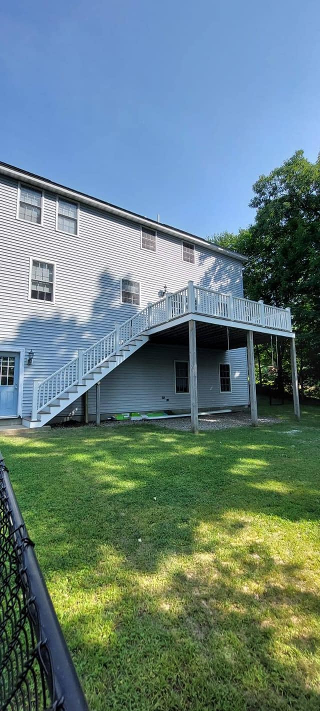 The back of a house with stairs leading up to the deck.
