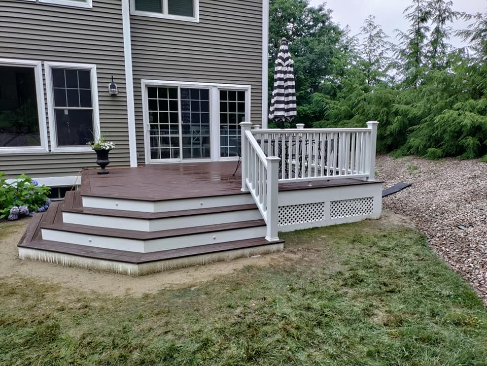 A deck with stairs and a white railing in front of a house.