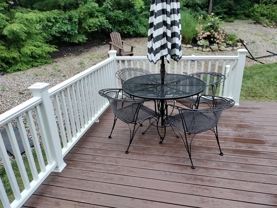 A deck with a table and chairs and an umbrella.