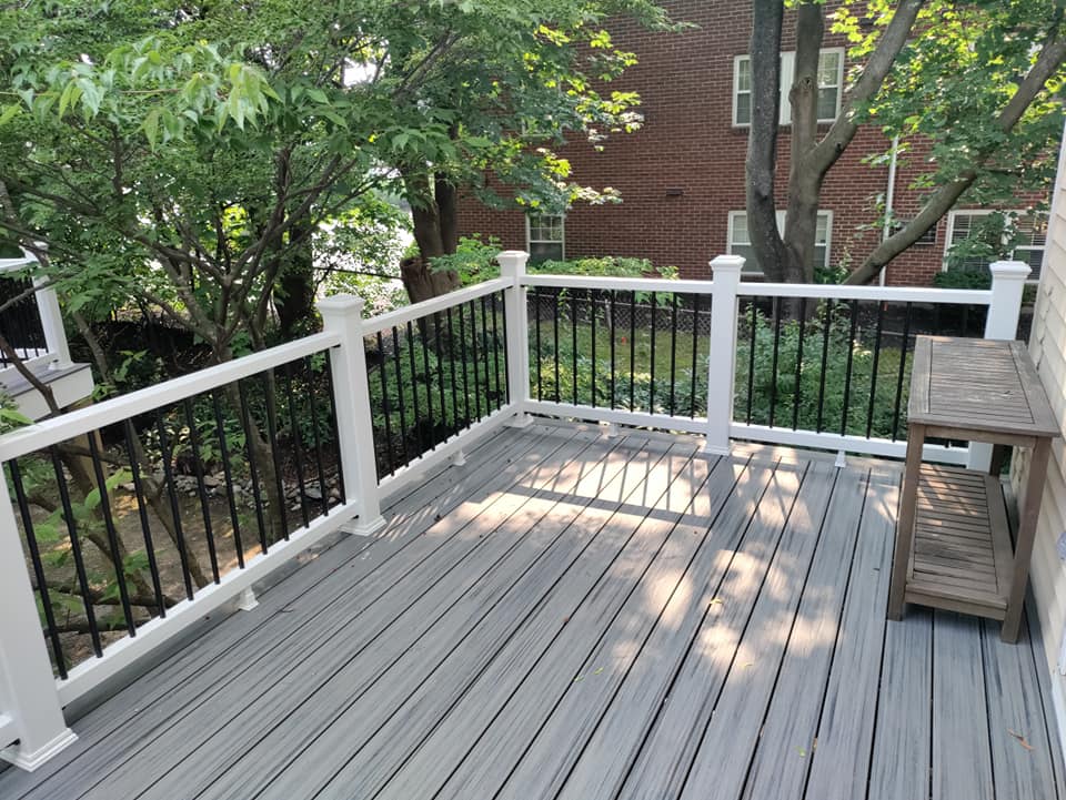 A wooden deck with a white railing and a bench.