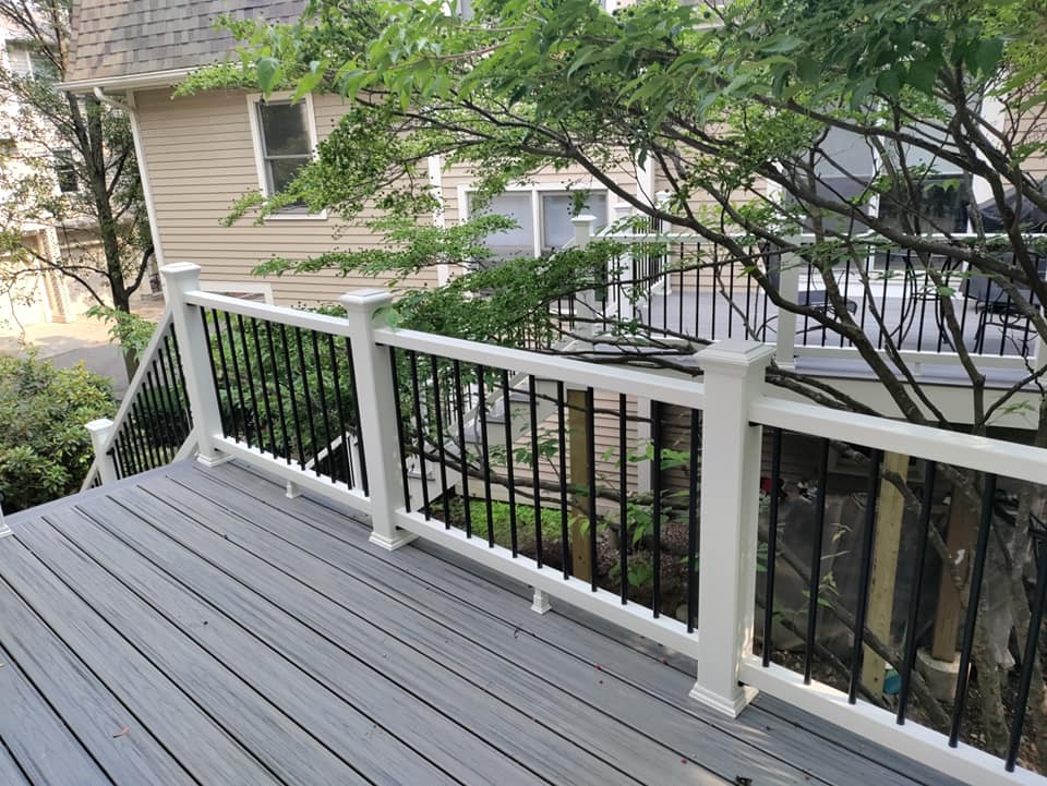 A deck with a white railing and a house in the background.