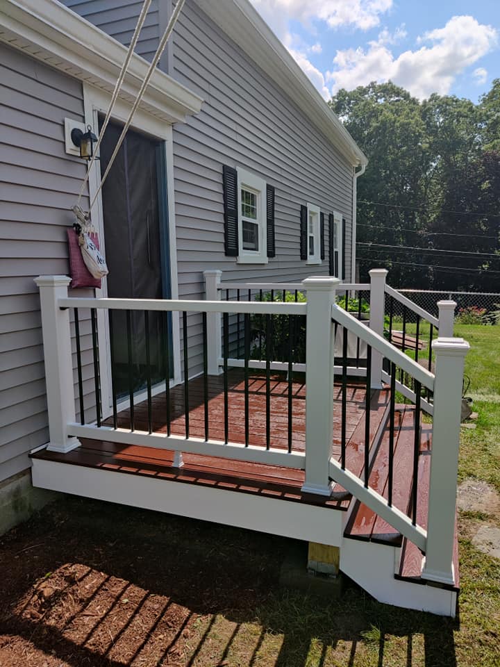 A gray house with a white deck and stairs