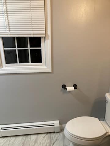A bathroom with a toilet , window and blinds.
