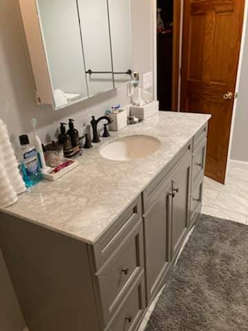 A bathroom with a sink , mirror and cabinets.