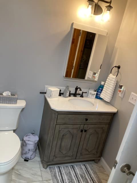 A bathroom with a toilet , sink and mirror.