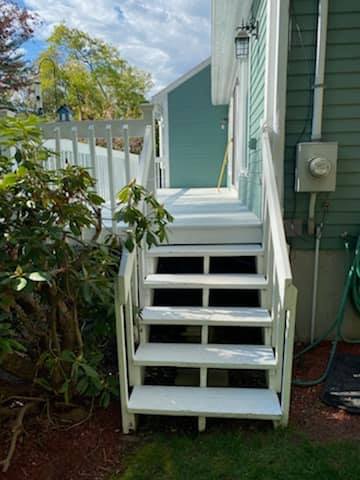 A set of white stairs leading up to a porch of a house.