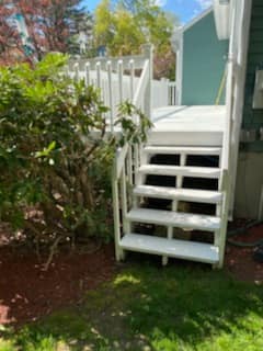 A white deck with stairs leading up to it.