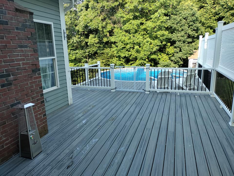 A large deck with a pool in the background.