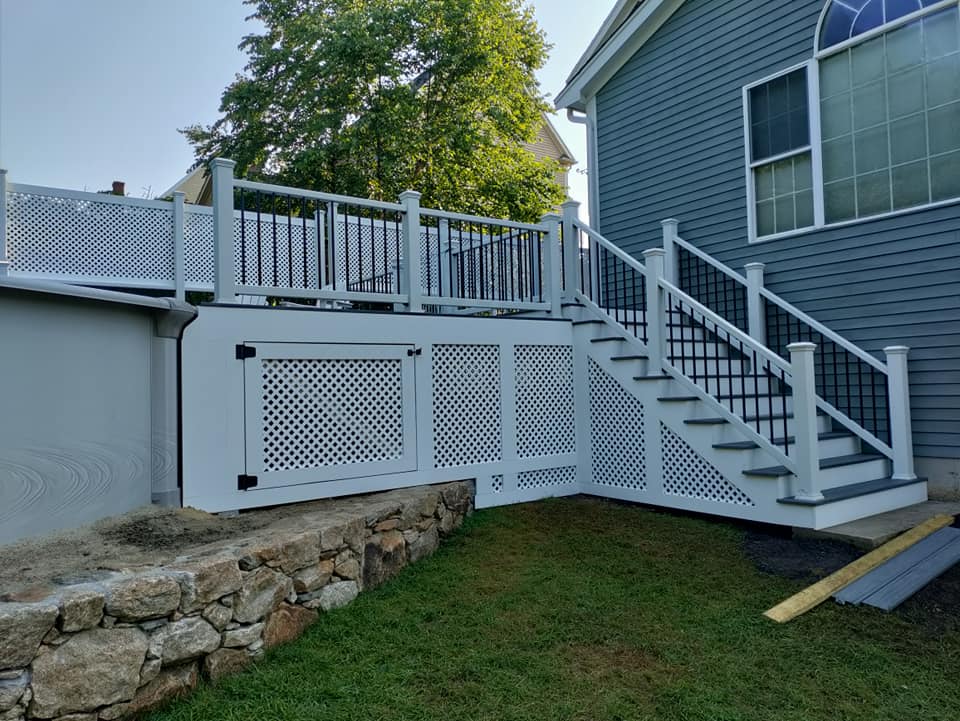 A white deck with stairs leading up to it next to a house.