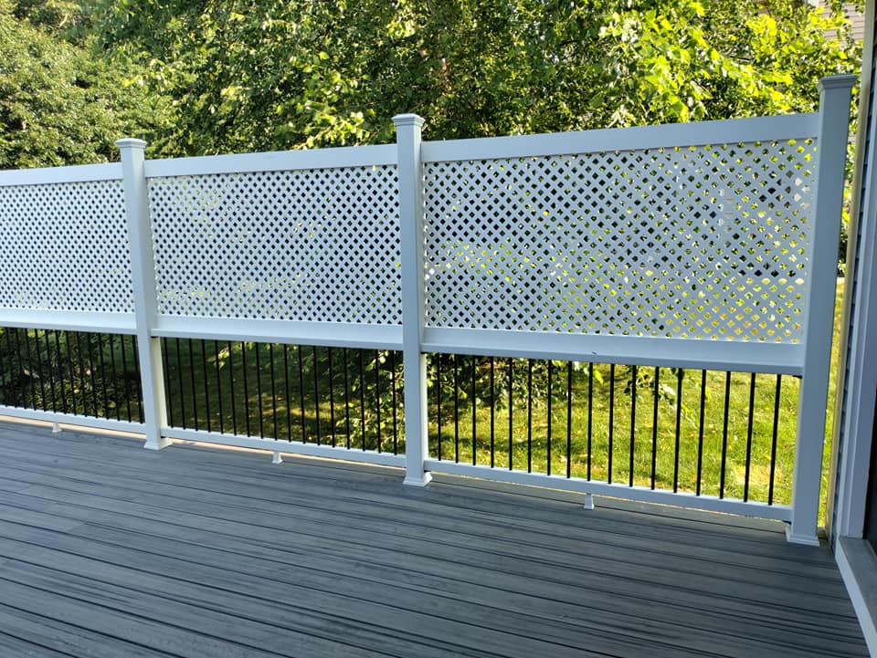 A deck with a white lattice fence and black railing