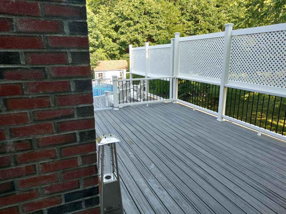 A wooden deck with a white fence and a brick wall