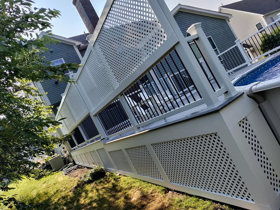 A white deck with a pool in the background