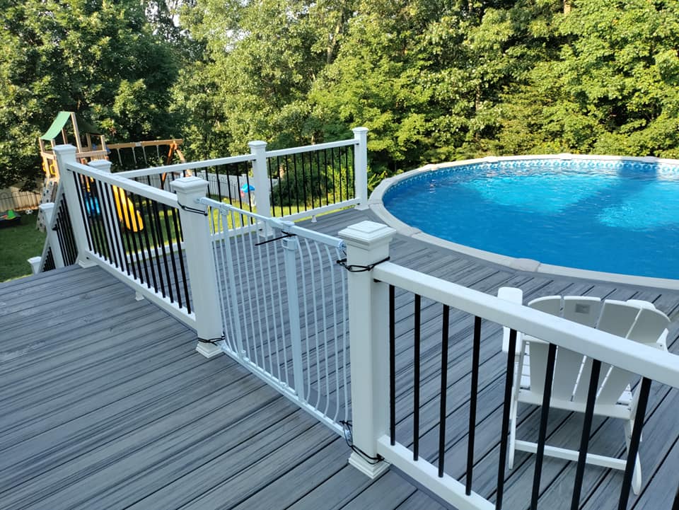 There is a swimming pool on the deck with a white railing.