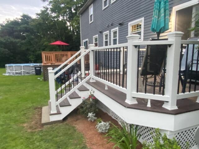 A deck with stairs leading up to it is in front of a house.