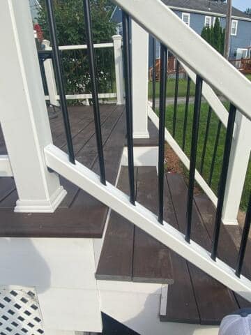 A close up of a deck with stairs and a white railing.