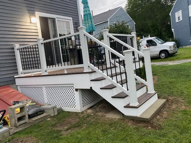 A deck with stairs leading up to it is being built in front of a house.