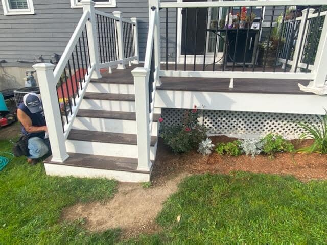 A woman is sitting on the steps of a deck.