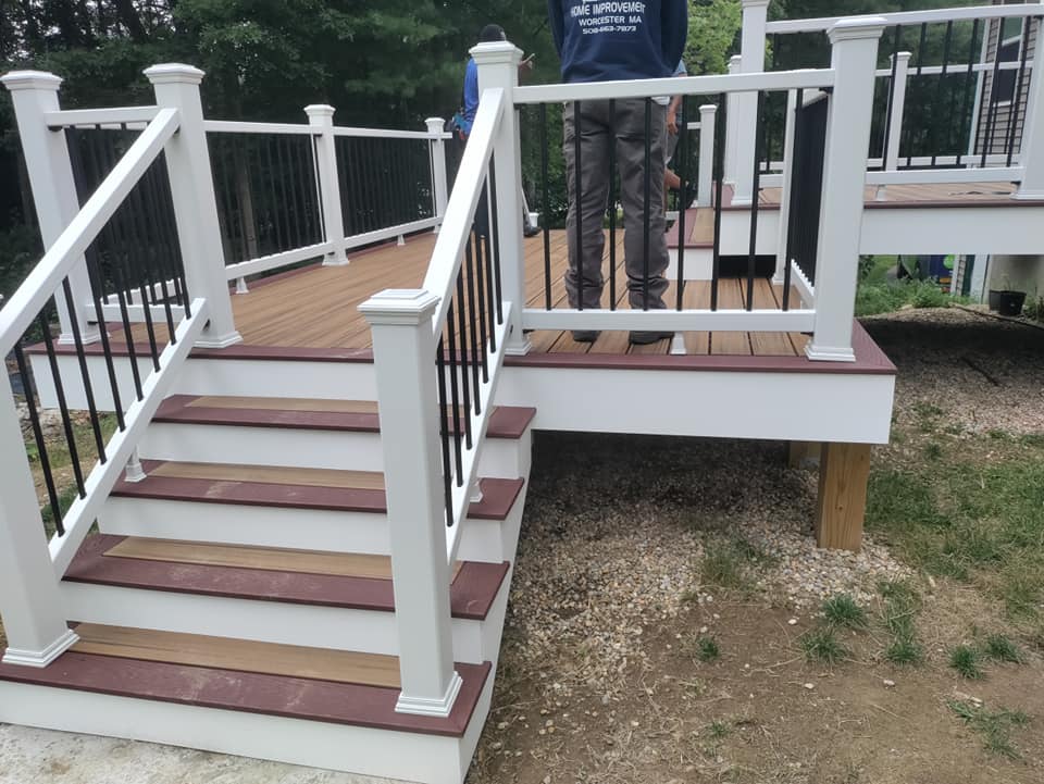 A man standing on a deck with stairs and a white railing