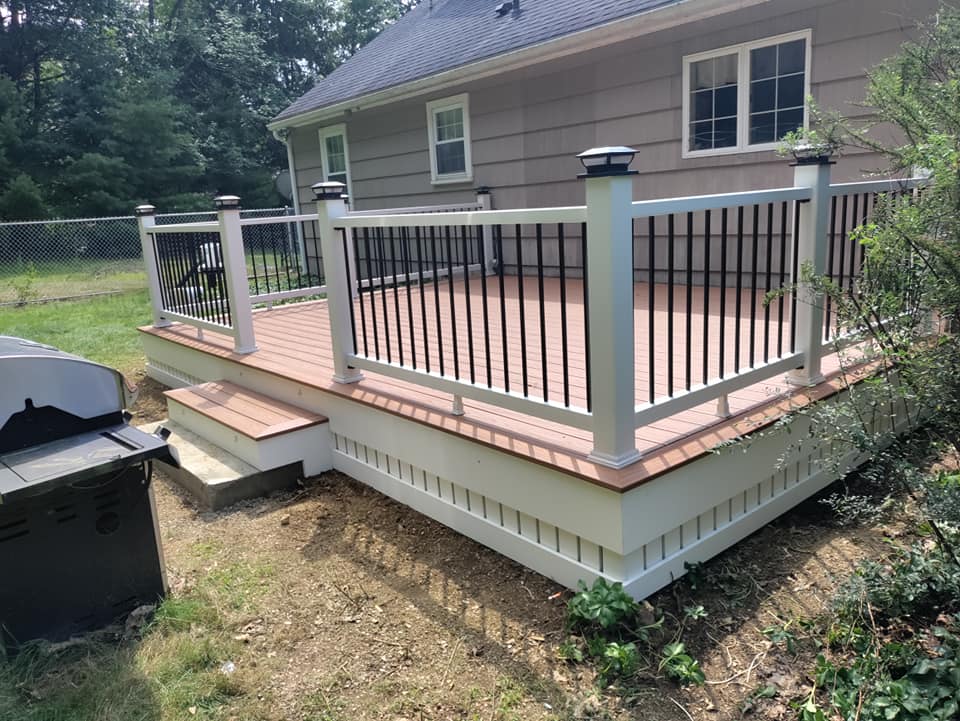 A deck with a white railing is in front of a house.