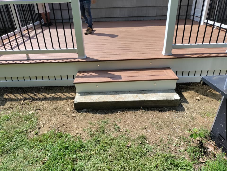 A person is standing on a deck with stairs and a railing.