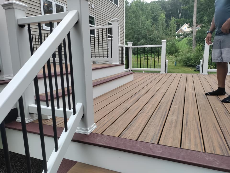 A man is standing on a wooden deck with stairs