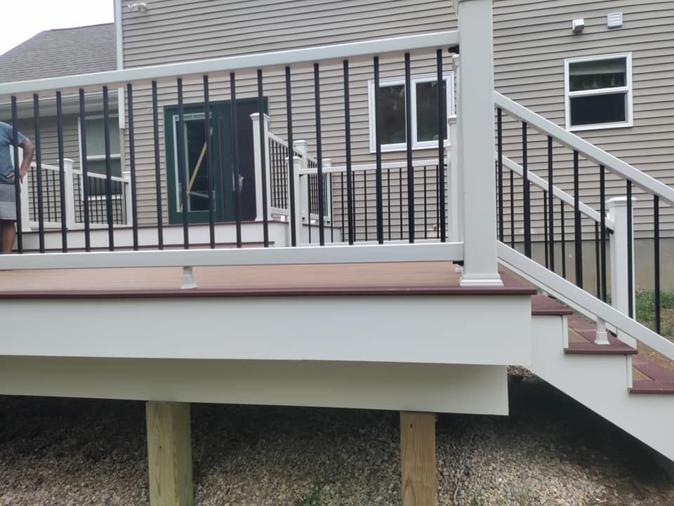 A white deck with black railing and stairs in front of a house