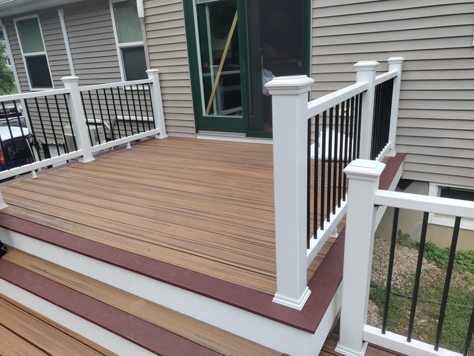 A wooden deck with a white railing is in front of a house.