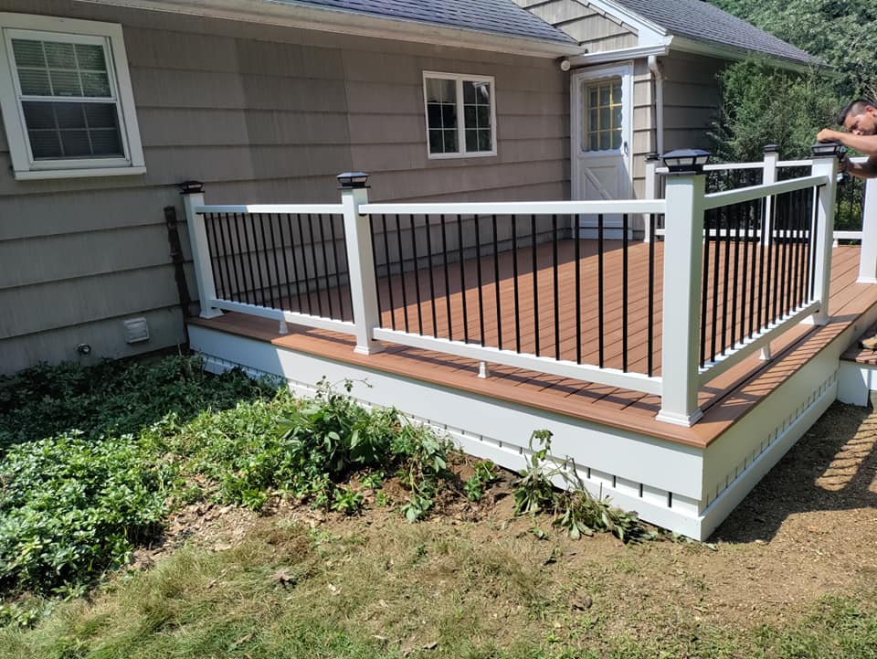 A deck with a white railing is in front of a house.