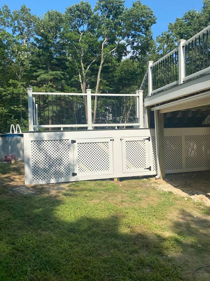 A white deck with a fence and a garage underneath it.