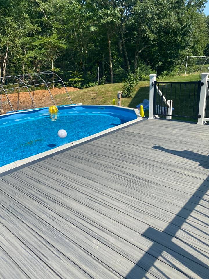 A large swimming pool is surrounded by a wooden deck.