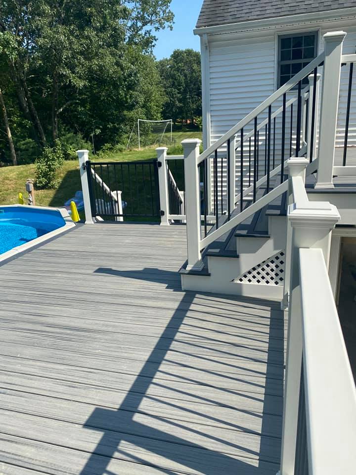 A wooden deck with stairs leading up to a pool.