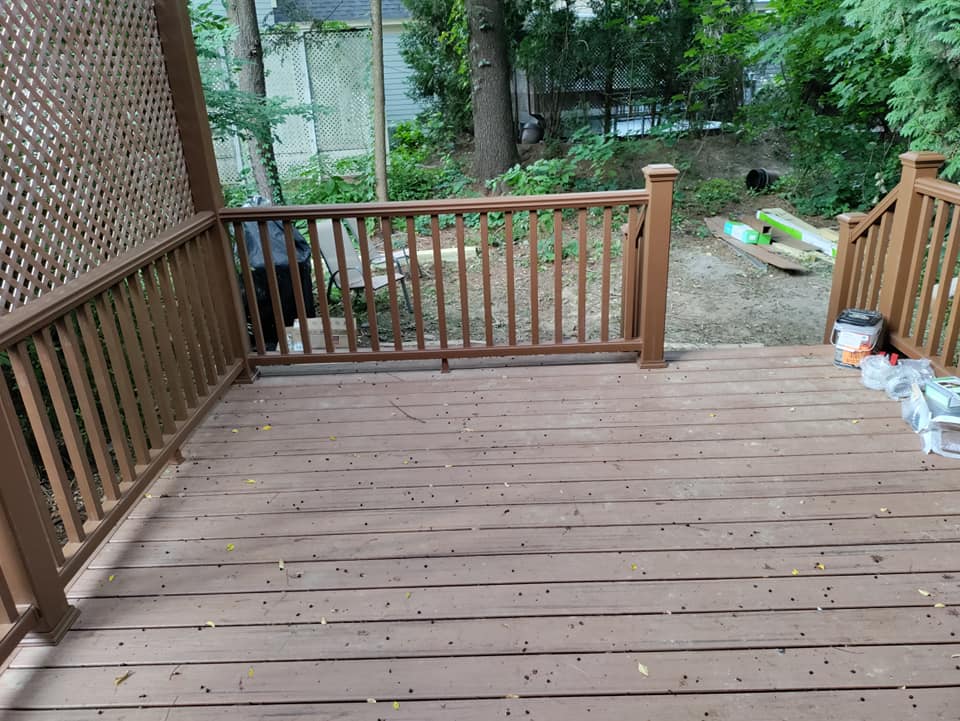 A wooden deck with a railing and stairs leading up to it.