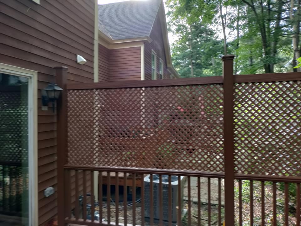 A wooden fence surrounds a deck in front of a house