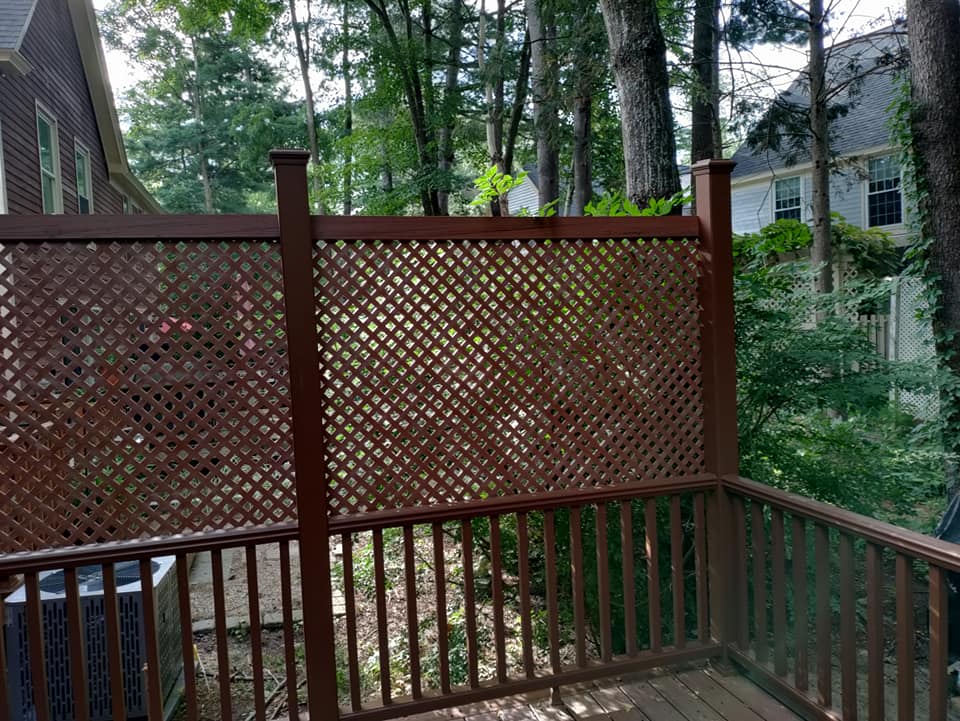A wooden deck with a fence and trees in the background.