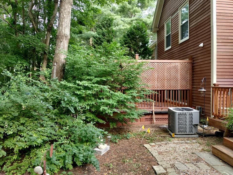 A house with a deck and an air conditioner in the backyard.